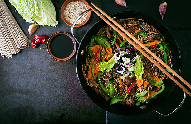 nouilles de sarrasin avec du bœuf, carottes, oignons et de poivrons - cuisine asiatique photos et images de collection