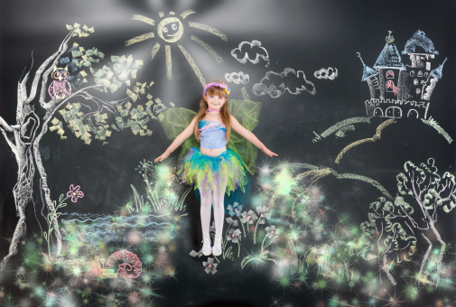 Beautiful little girl dressed as fairy soaring in the fantastic wood. Illusion on background with chalk drawing