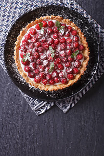Delicious raspberry tart with cream and mint vertical top view