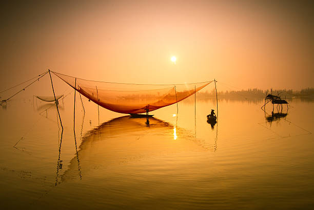 Fisherman checks his nets on river in Hoian, Vietnam Unidentified fisherman checks his nets in early morning on river in Hoian, Vietnam hoi an stock pictures, royalty-free photos & images