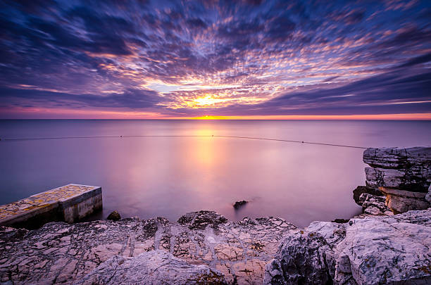 Beautiful sunset with smooth water, rocks in the foreground and silky sea