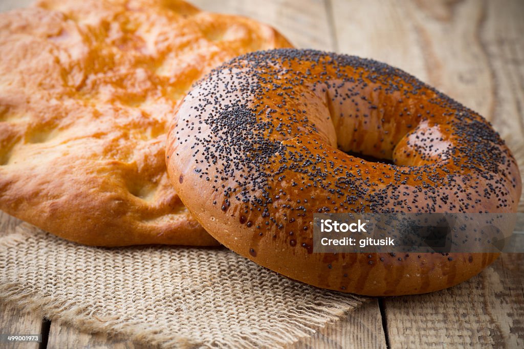 Bread. Freshly baked bread with poppy seeds on a wooden background. Baked Stock Photo