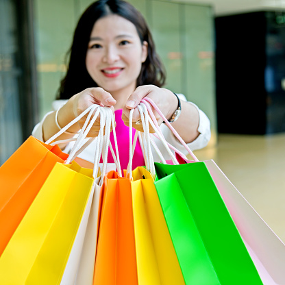 Attractive young asian woman holding shopping bags at mall.
