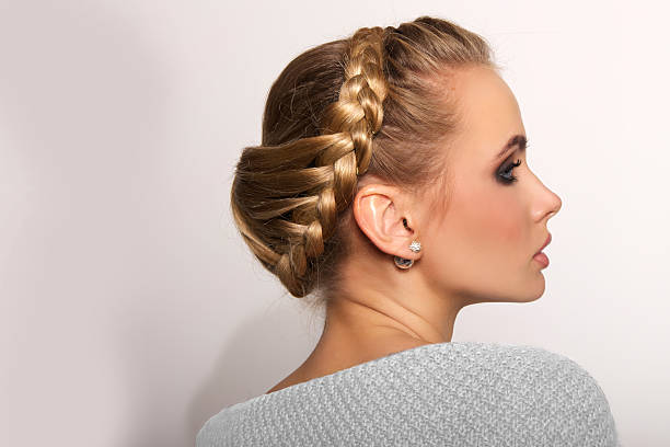 portrait of a beautiful young blonde woman portrait of a beautiful young blonde woman on a light background with hairdo on her head. copy space. braided buns stock pictures, royalty-free photos & images