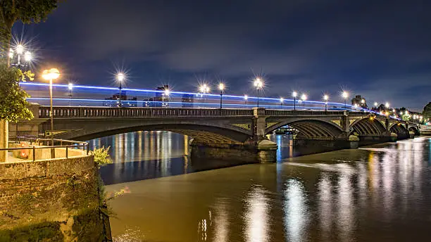 Vibrant colourful perspective view of Battersea bridge, London, at night as seen from the south bank of the Thames river.