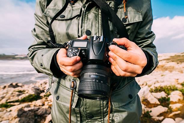 Young man holding camera A young man holding a DLSR camera in a natural environment. slr camera stock pictures, royalty-free photos & images