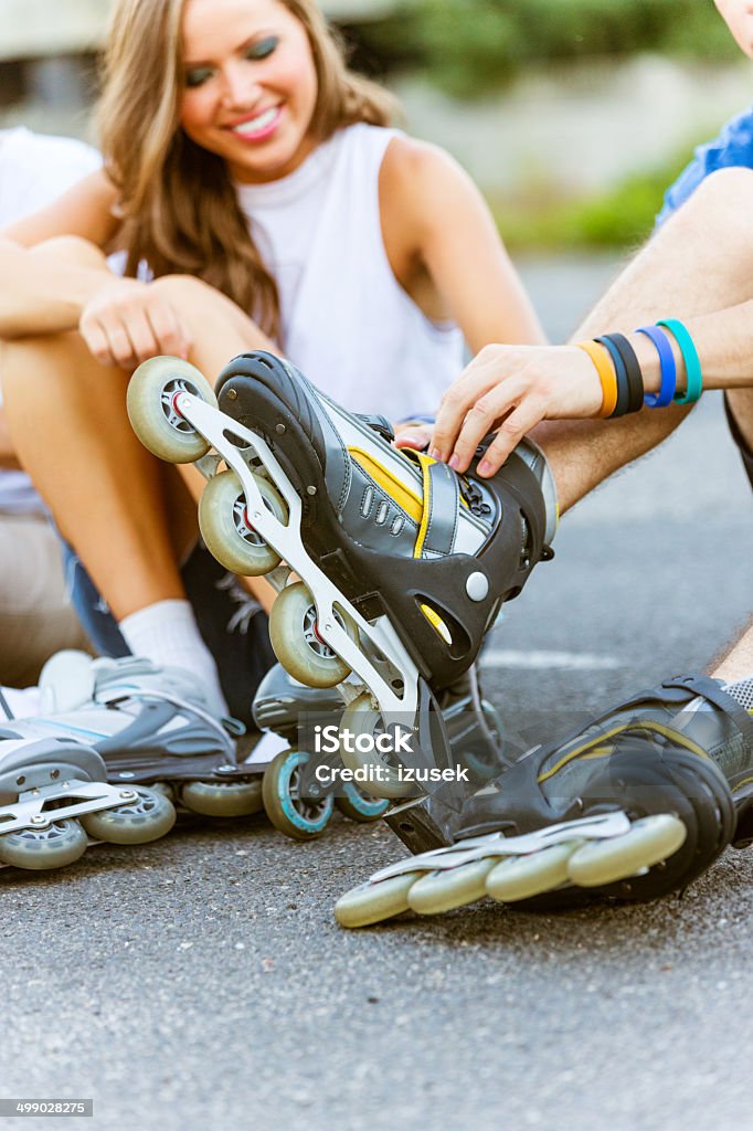 Young people on rollerblades Friends sitting on tarmac and tying rollerblades. Close up of legs. 20-24 Years Stock Photo