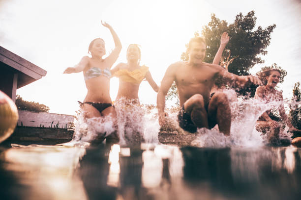 istock Young people splashing into a pool having jumped in together 499031102