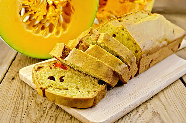 Fruitcake pumpkin with candied fruits on a plate, pumpkin cut against a wooden board