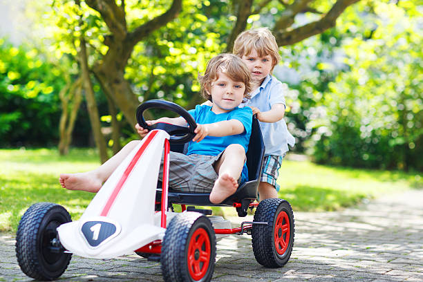 istock Two happy twin boys driving toy car 499031775