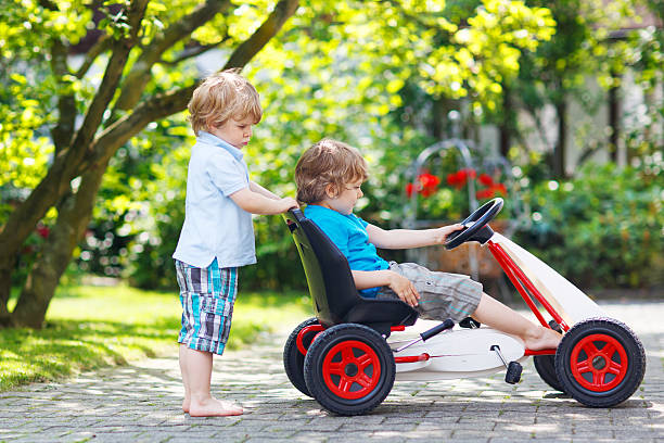 istock Two happy twin boys driving toy car 499031777