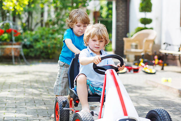 istock Two happy twin boys driving toy car 499031779