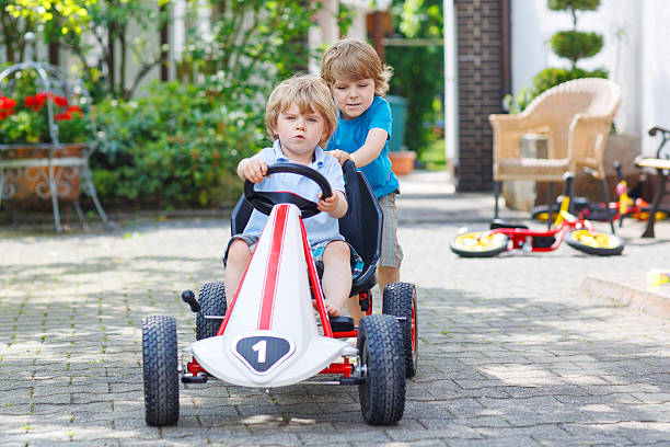 Two happy twin boys driving toy car