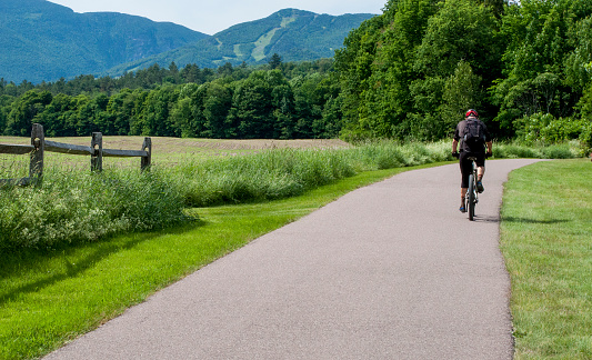 Stowe, Vermont, USA-June 23, 2014: A bicycle rider pedals over the Recreation Path in Stowe, Vermont. This path is used by all kinds of people seeking to exercise while enjoying the scenery on this 5.5 mile path which winds through fields and woods in this northern Vermont town.