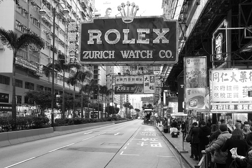 Hong Kong, China - January 4, 2012: Vintage scene along the Nathan Road (Golden Mile), the main thoroughfare on the Kowloon side of Hong-Kong, China. A huge Rolex adverstisment is dominating the composition. Chiana is a significant and increasing market for Swiss watches.