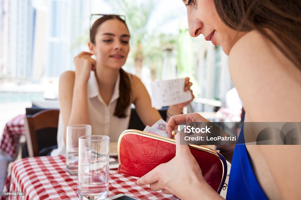 Paying the check at the restaurant Two european friends collecting money to paying in a restaurant in Dubai Marina, after their lunch break in summertime. Gratuity Stock Photo