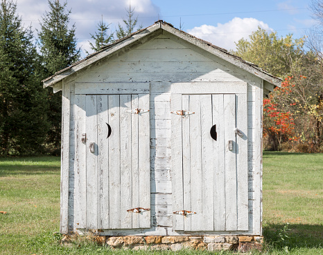 An old white two seater outhouse.