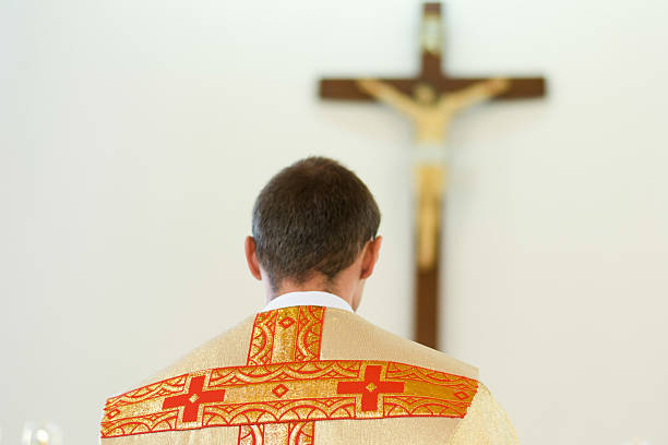 istock Catholic priest in yellow bows to Crucifixion 499048686