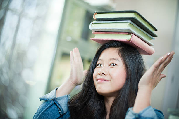 istock Happy Asian girl student balancing stack of books on head. 499052158
