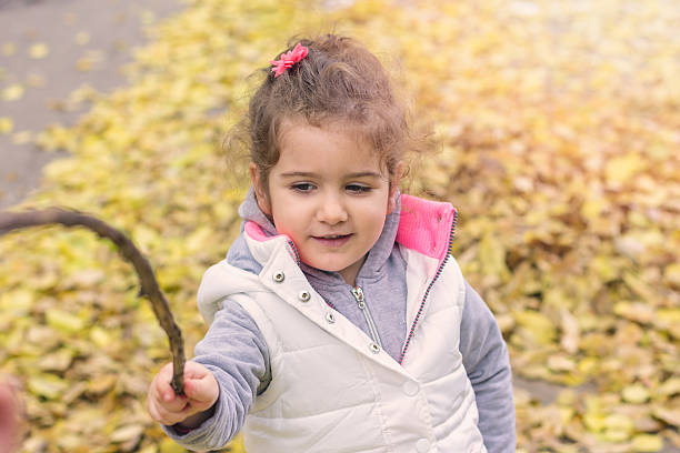 istock child enjoys playing with leaves while holding branch 499052616