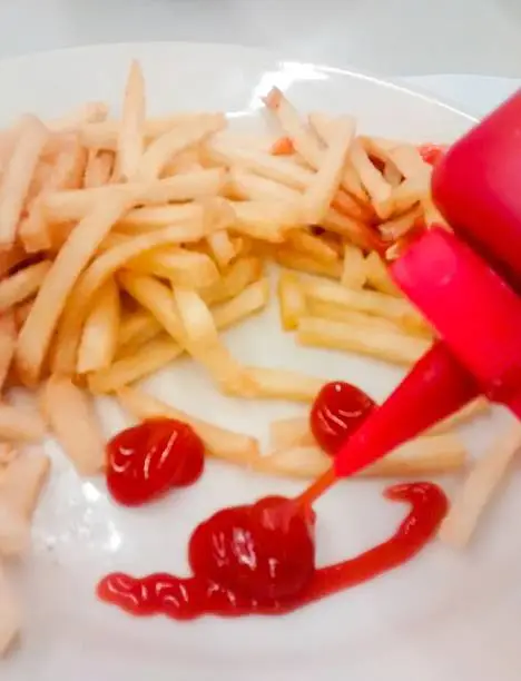 Ketchup condiment squirted unto plate in form of smiley happy face 
