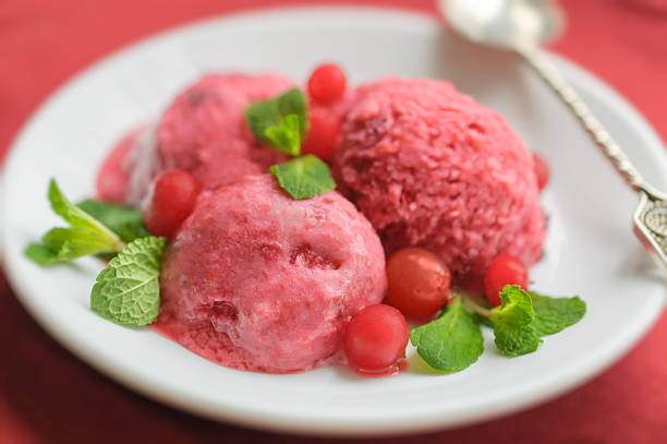 Ice cream with berries and mint on a white plate