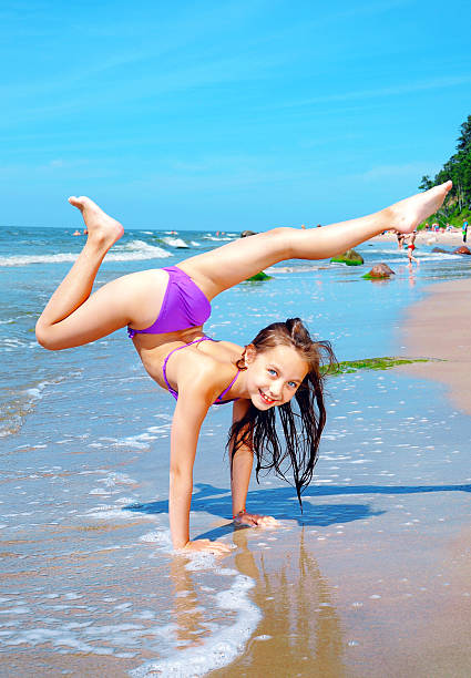 Flexible little girl playing on beach stock photo