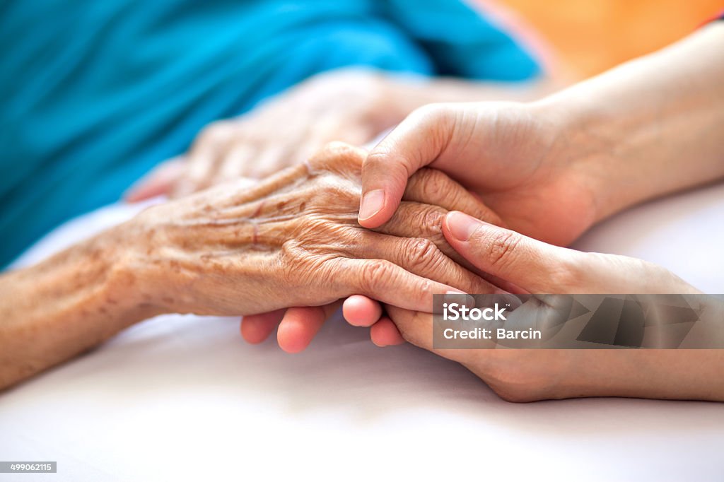 Helping the needy Woman holding senior woman's hand on bed Senior Adult Stock Photo