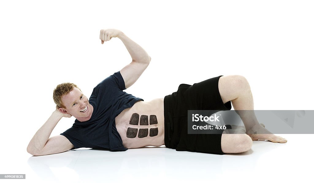 Cheerful man lying on ground with fake six pack Cheerful man lying on ground with fake six packhttp://www.twodozendesign.info/i/1.png 20-29 Years Stock Photo