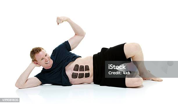 Cheerful Man Lying On Ground With Fake Six Pack Stock Photo - Download Image Now - 20-29 Years, 25-29 Years, Abdominal Muscle
