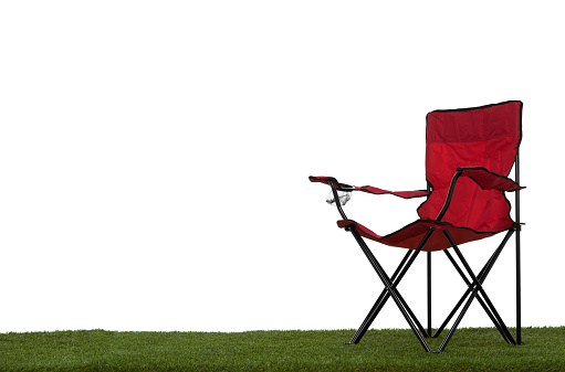 Folding camp chair angled on grass with white background