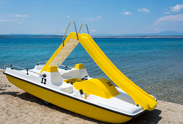 istock Yellow pedal boat on a beach 499086265