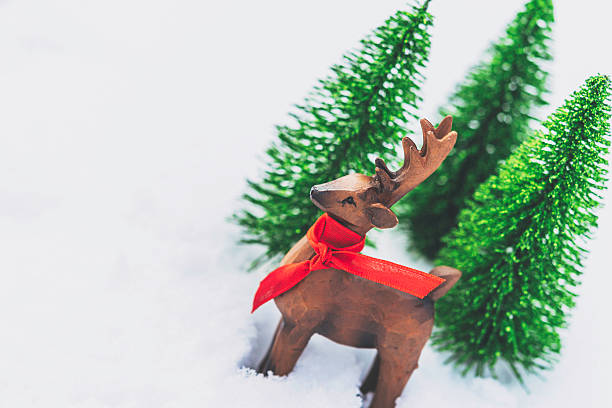 istock Wooden deer in real snow with tiny trees in background 499087646