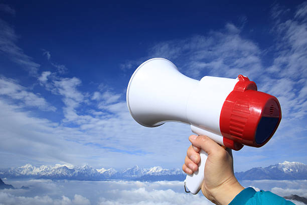 istock hand hold loudspeaker to blue sky on mountain peak 499089196