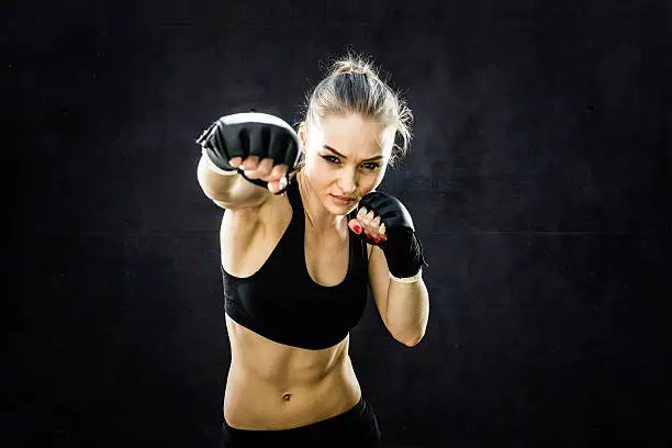 Women Fighter Punching White Background.  Wearing black sparing gloves.