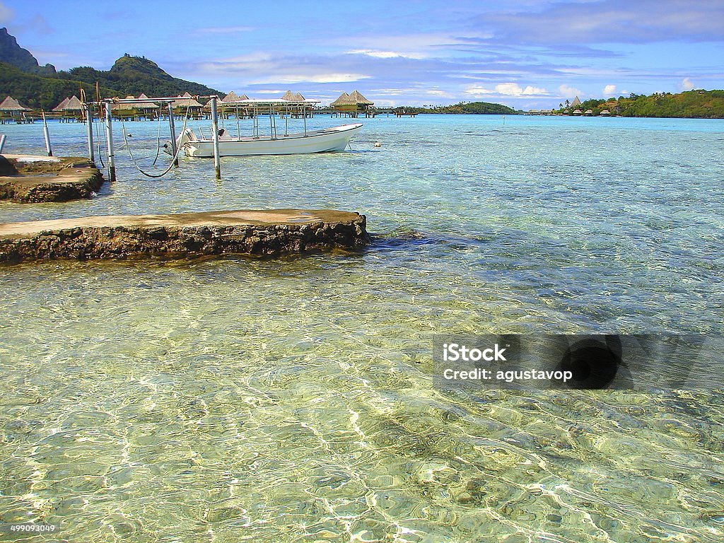 Bora Bora Bungalows and fishing boat pier on turquoise beach, Polynesia You can see in the link below my page of FRENCH POLYNESIA DREAMING BEACHES (Rangiroa, Bora Bora, Moorea, Huahine, Tahiti) stunning idyllic turquoise beaches and culture, sunrises, sunsets, etc!! Beach Stock Photo