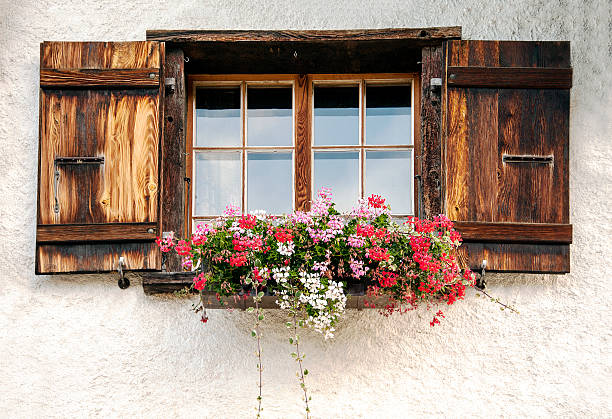 Wooden Swiss chalet window with flower box typical of the canton Valais.