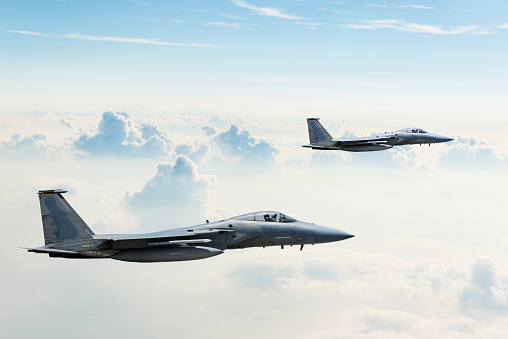 Two F-15 Eagle fighter jets flying above clouds