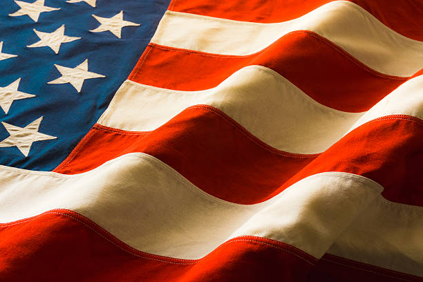 Antique American Flag Draped (P) A vintage American Flag lays draped on a table in warm light. vintage american flag stock pictures, royalty-free photos & images