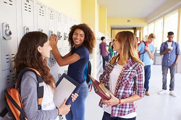 Group Of Female High School Students Talking By Lockers Smiling