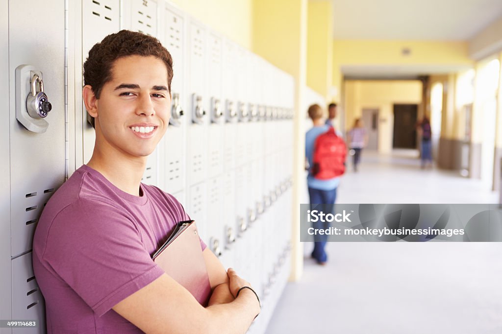 Male High School Student Standing By Lockers Male High School Student Standing By Lockers Smiling Latin American and Hispanic Ethnicity Stock Photo