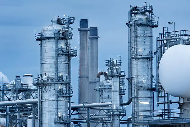 Oil refinery towers and steel pipes at dusk. Maasvlakte, Europoort, The Netherlands.