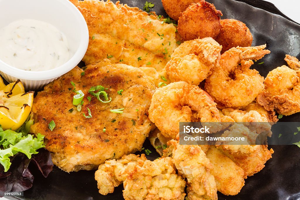 Fried seafood platter. Fried seafood platter with fish, shrimp, oysters, hush puppies, and a crab cake. Fried Stock Photo