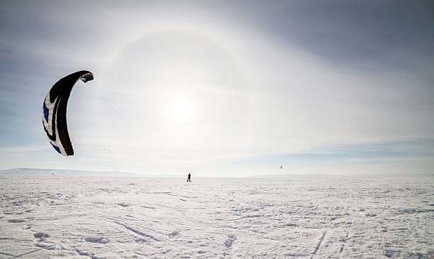 istock Kiteboarder with blue kite on the snow 499124451