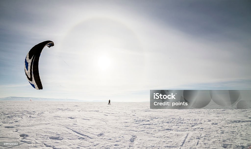 Kiteboarder with blue kite on the snow Kite surfer being pulled by his kite across the snow Activity Stock Photo