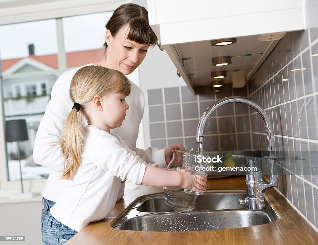 Mother and Daughter in the kitchen Small Girl in the kitchen with her mother drinking water Drinking Water Stock Photo