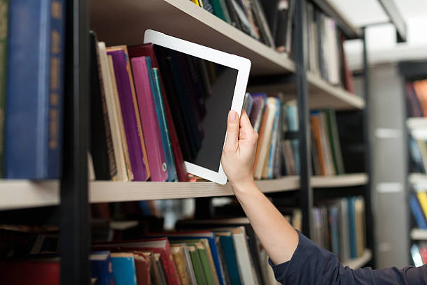 istock tablet picked with hand from book shelf in the library 499126996
