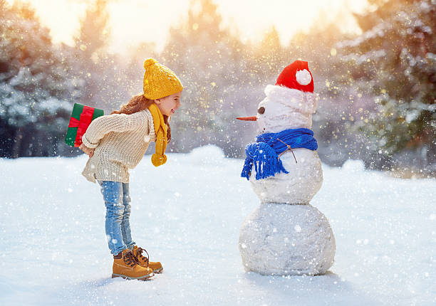 istock girl playing with a snowman 499130454