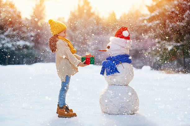istock girl playing with a snowman 499130550