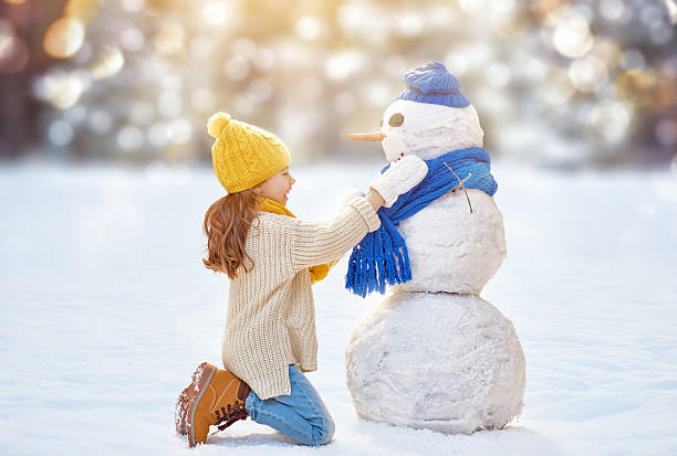 istock girl playing with a snowman 499130640